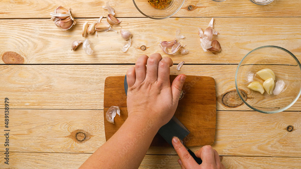 Αυτοκόλλητο Close-up of women's hands crushing garlic cloves with a knife