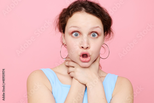 woman in blue t-shirt strangles herself emotions pink background