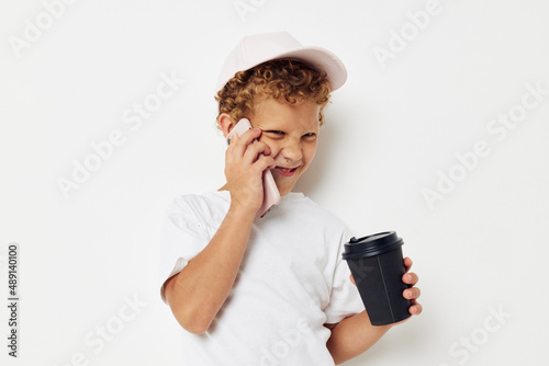 Photo portrait curly little boy what kind of drink is the phone in hand communication isolated background unaltered