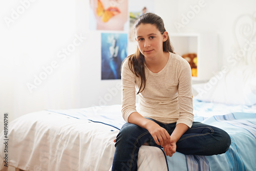 A day in the life of a teen. Portrait of a teenage girl sitting on her bed at home.