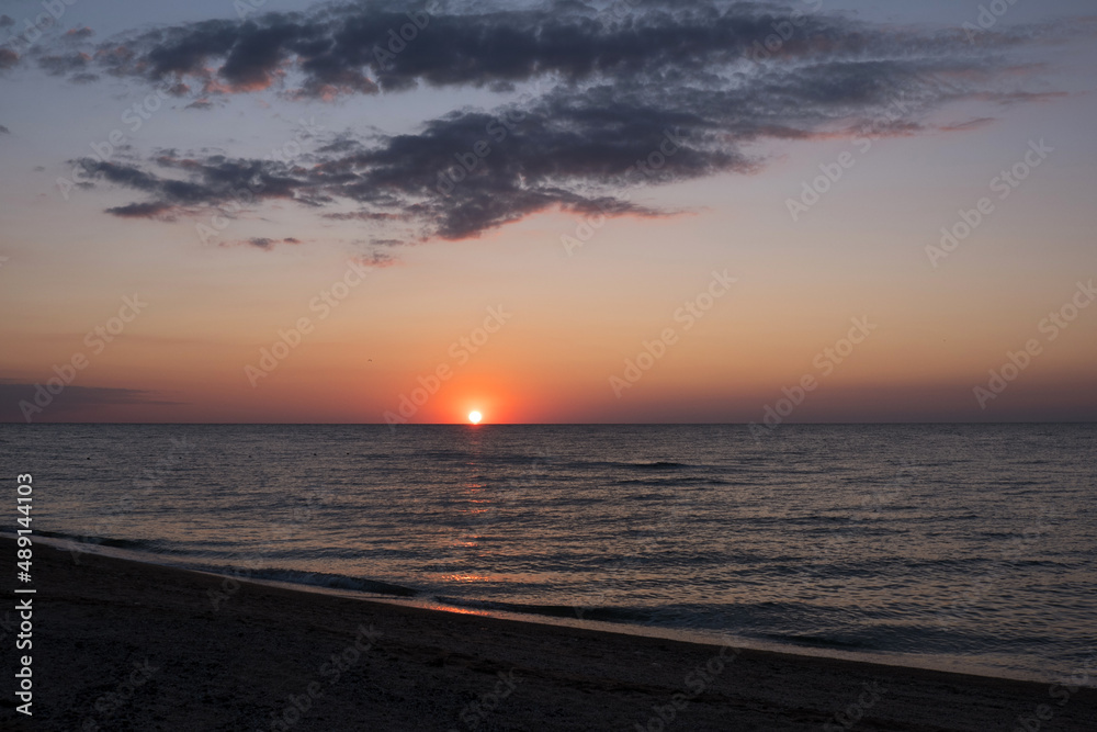 Beautiful sunset over sea with reflection in water, majestic clouds in the sky