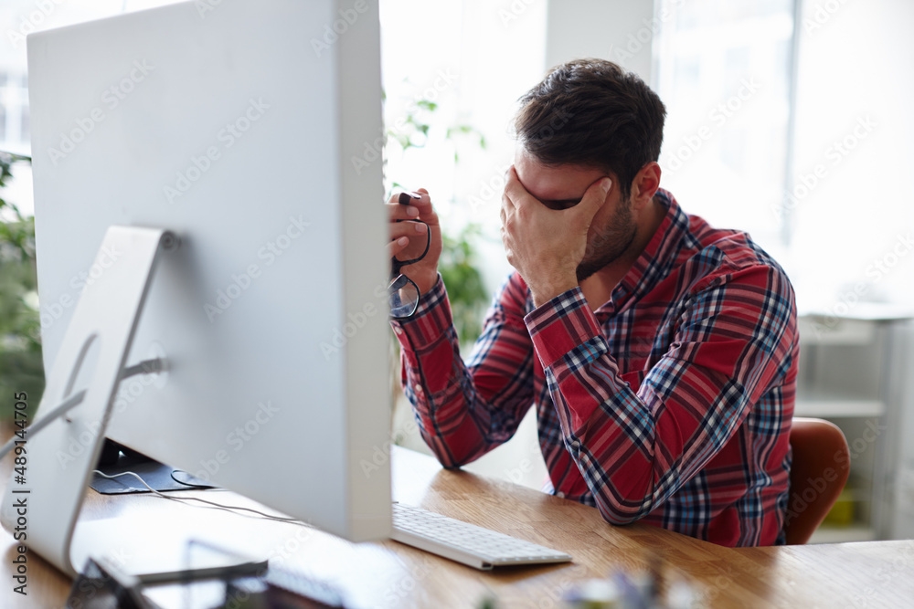 Need more energy to maintain your edge. Shot of a casual young designer holding his head in despair.