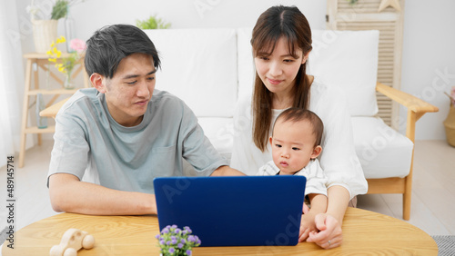 赤ちゃんにノートパソコンを見せる両親