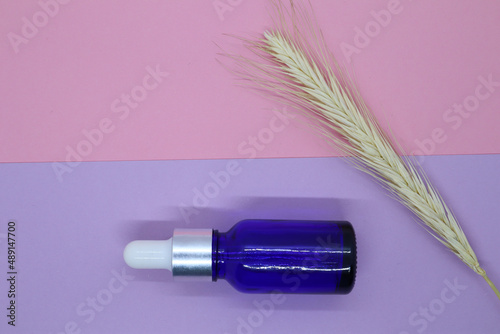 Container  blue cosmetic bottle and dried flowers on a pink background. Blank label for branding mockup. Gift set for sale promotion.
