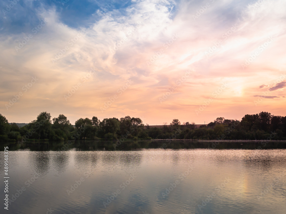 A beautiful sunset on a lake, river or pond with blue skies and clouds.