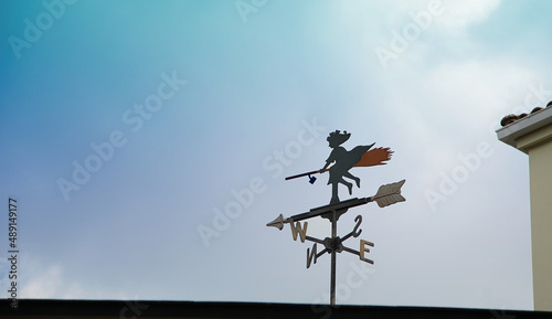 A weathervane on the roof of a house on a sunny blue sky day