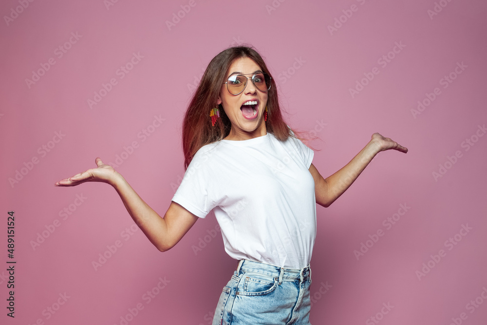 Happy surprised young fashion model woman in white t-shirt on colorful pink studio background Happy surprised young fashion model woman in white t-shirt on colorful pink studio background