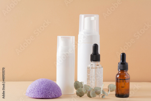 Facial cosmetic products and konjac sponge on a beige background