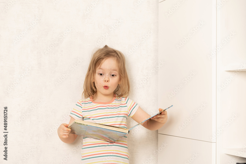 Surprised child stands and studies a book Surprised child stands and studies a book