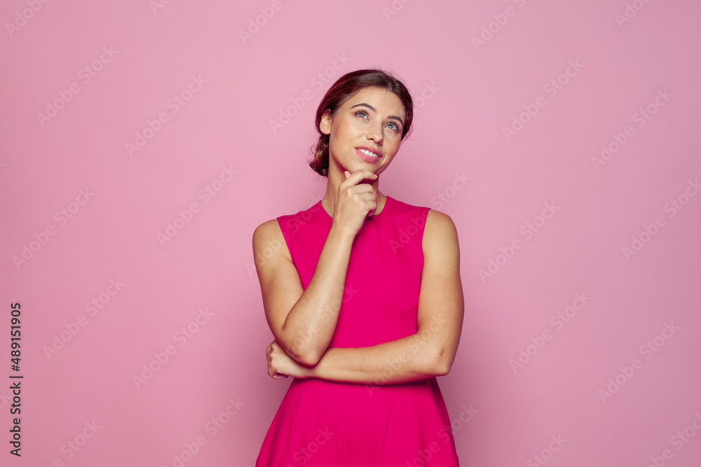 Studio portrait of beautiful young woman thinking and looking upwards. Creative person portrait. Concept of perception and reflection.