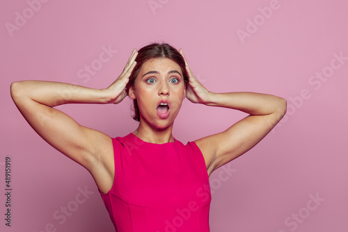Cute worried nervous woman with panic expression on pink color background