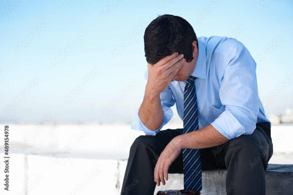 Fighting deppression. An upset corporate man sitting on the rooftop of a building with his head in his hands. Fighting deppression. An upset corporate man sitting on the rooftop of a building with his head in his hands.
