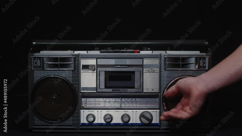 A man's hand turns the frequency adjustment knob of an old fm receiver on a black background A man's hand turns the frequency adjustment knob of an old fm receiver on a black background