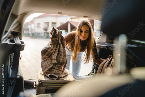 One young beautiful woman student travel concept female take luggage baggage suitcase and other stuff and belongings from the back of her car while moving into dormitory on college campus real people