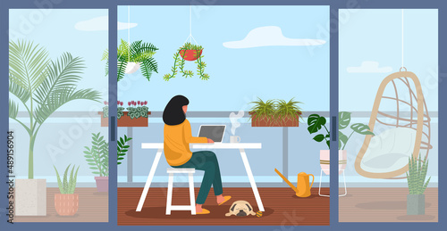 Tela A woman working on laptop on apartment balcony decorated with green plants