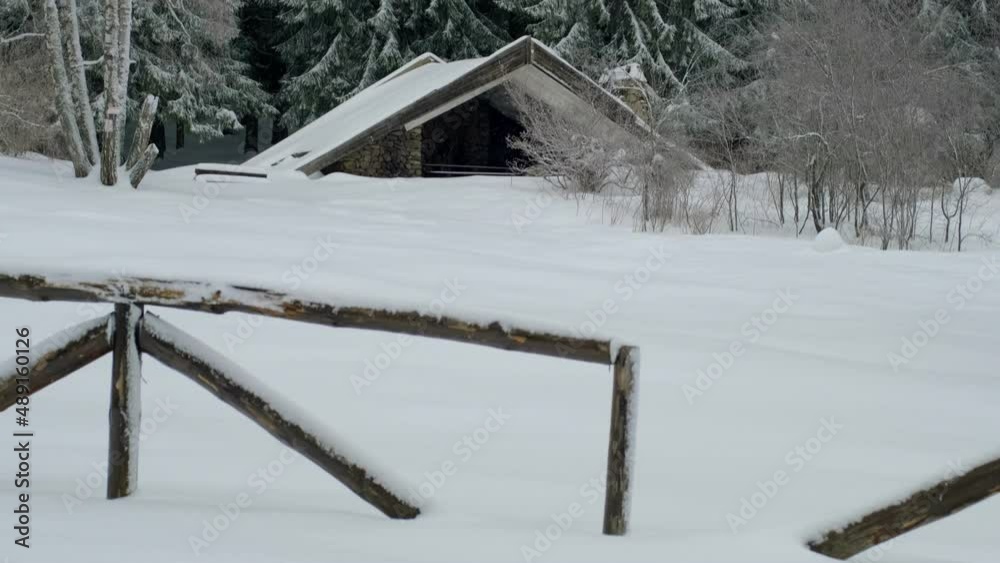 High-mountain shelter winter landscape in the woods in the background and a wooden fence in the foreground - all covered with deep, virgin snow at daytime. High-mountain shelter winter landscape in the woods in the background and a wooden fence in the foreground - all covered with deep, virgin snow at daytime.
