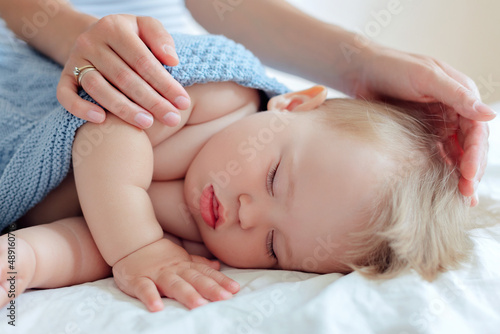 sleeping small child close-up, mother's hands cover a one-year-old baby with a blanket