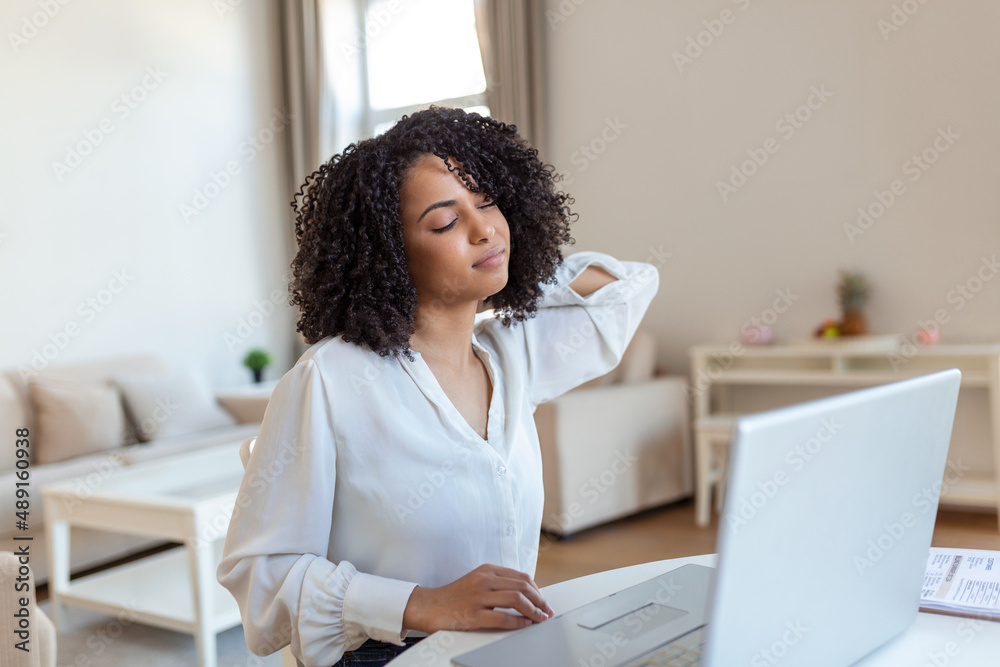 Businesswoman feeling pain in neck after sitting at the table with laptop. Tired female suffering of office syndrome because of long hours computer work. Pretty girl massaging her tense neck muscles Businesswoman feeling pain in neck after sitting at the table with laptop. Tired female suffering of office syndrome because of long hours computer work. Pretty girl massaging her tense neck muscles