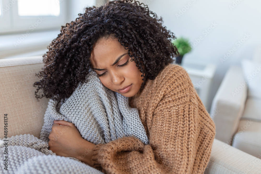 Sick young african woman feeling cold covered with blanket sit on bed, ill  black girl shivering freezing warming at home wrapped with plaid, no  central heating problem, fever temperature flu concept Photos