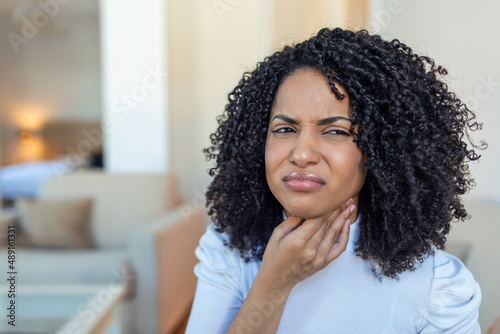 Photo Close up of young woman rubbing her inflamed tonsils, tonsilitis problem, cropped
