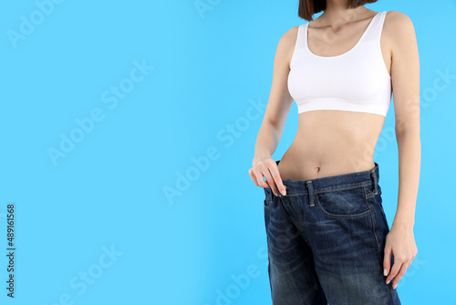 Concept of weight loss with young slim woman on blue background © Atlas