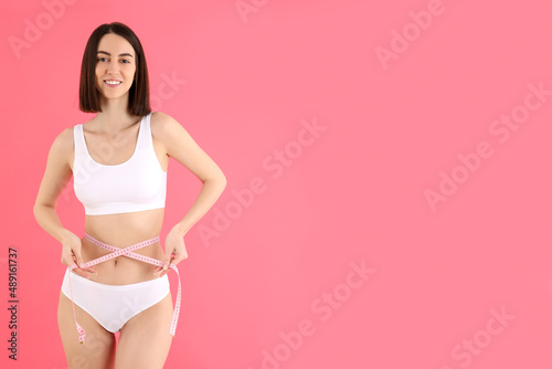 Concept of weight loss with young slim woman on pink background © Atlas