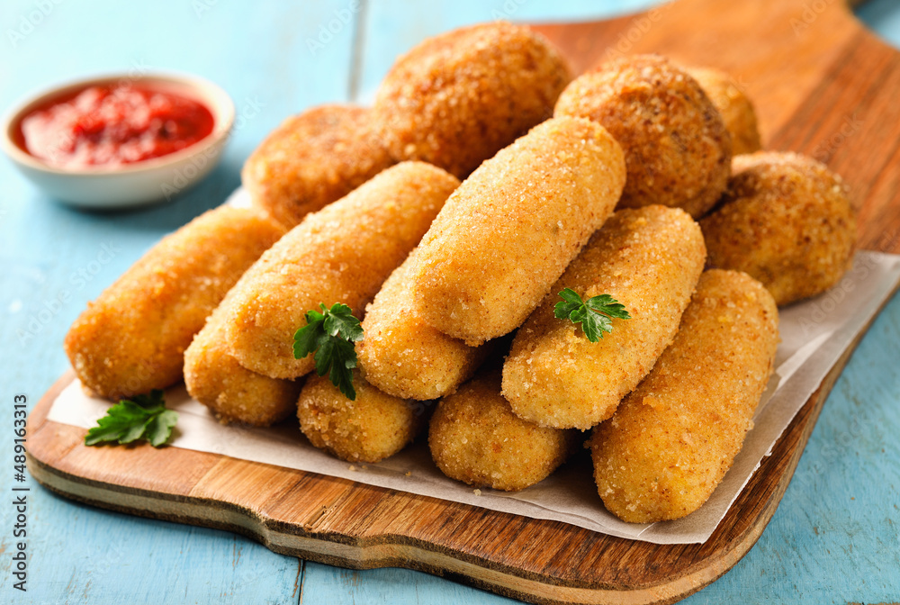 Homemade POTATO CROQUETTES in various shapes on a cutting board