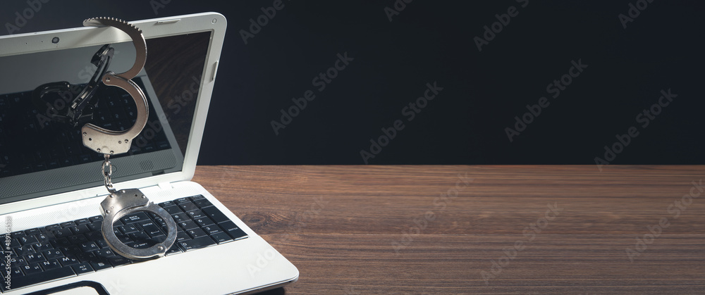 Handcuffs on the computer keyboard. Cyber crime