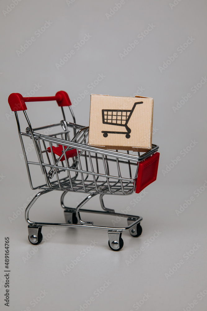 Shipping boxes in shopping cart trolley close-up, shopping and commerce concept. Vertical image
