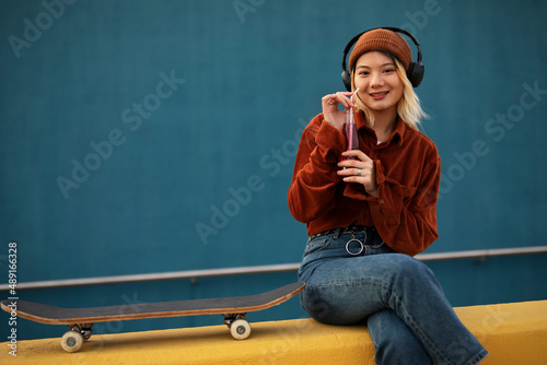 Fashion woman with skateboard. Urban woman listening the music.