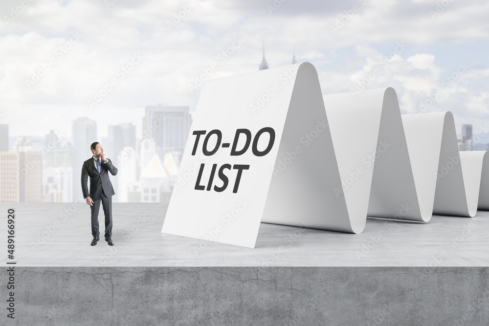 Obraz premium Attractive young european businessman looking at to-do list on concrete white city background. Checklist and busy concept.