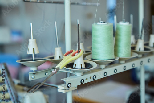 Industrial sewing production or atelier. Threads for sewing at the factory and creating clothes from fabrics. Sewing machines close-up.