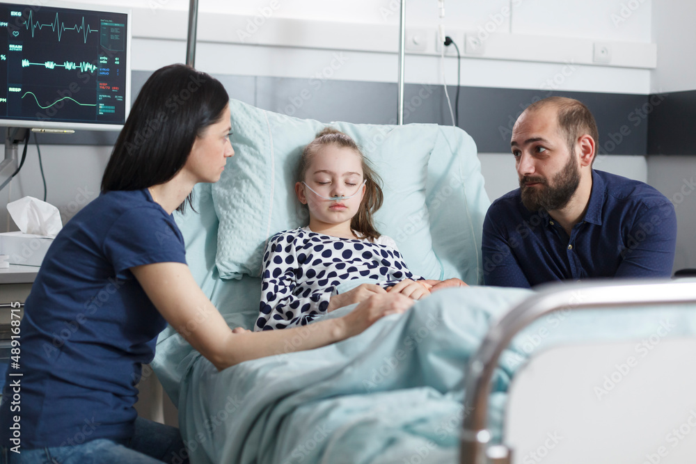 Obraz premium Young worried uneasy parents discussing about little daughters disease evolution while in pediatric clinic patient recovery ward room. Anxious stressed couple talking about healthcare treatment.