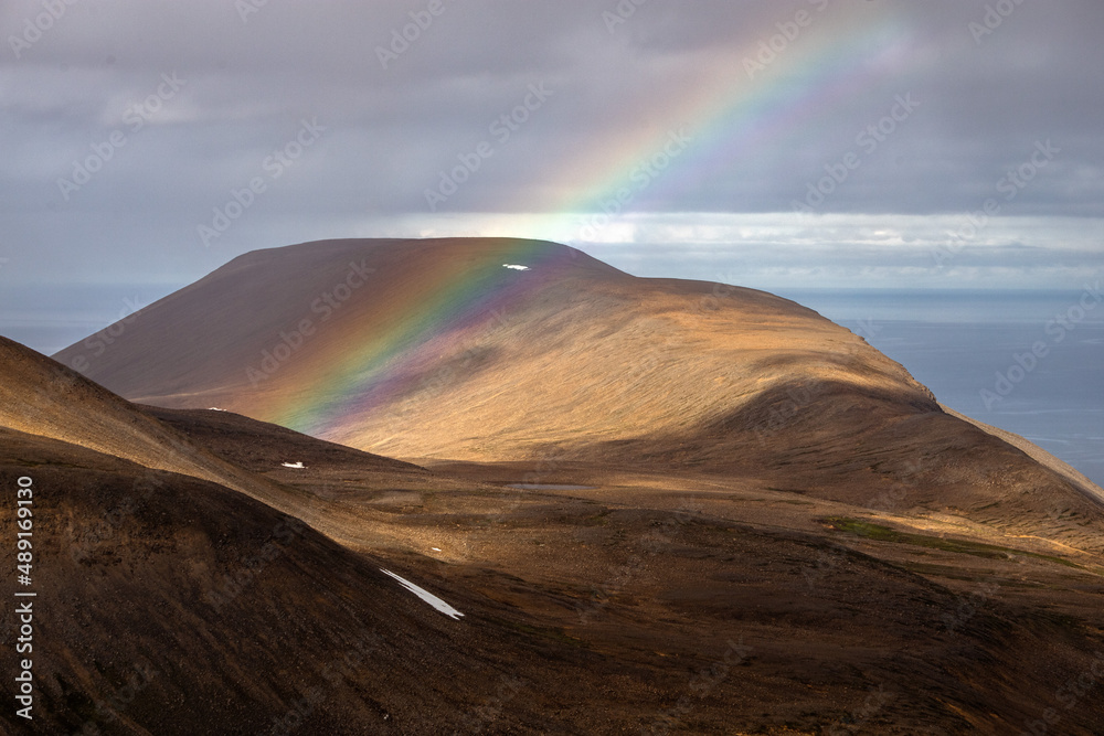 A mountain full of gold in Iceland, with a shining rainbow on the landscape