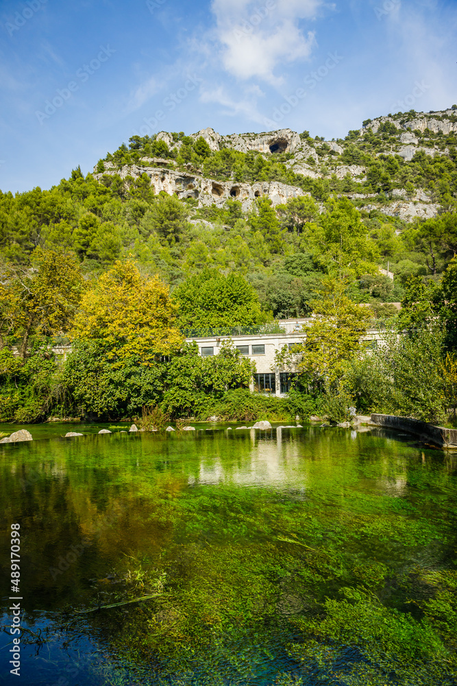 Sorgue river and limestone mountains in Fontaine de Vaucluse village in Provence, France on a summer day