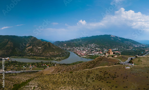 Distance aerial wide panorama view of Jvari clifftop orthodox monastery located in Mtskheta Georgia. Summer day time. Travel and vacation concept. Copy space. Mtkvari river.