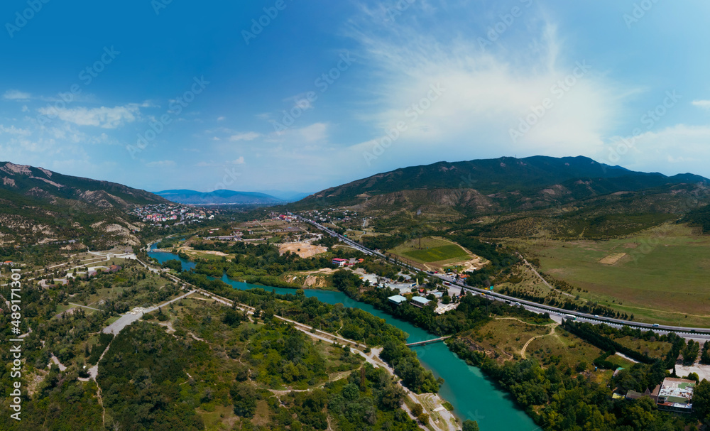 A place where two rivers of different colors meet. Wide aerial view panorama. Mountains. Travel and vacation concept. Summer day. Tsitsamuri in Georgia.