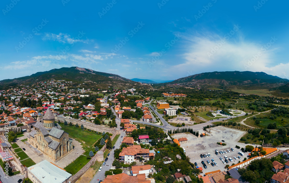 Beautiful aerial view of streets of Mtskheta village in Georgia. Mtkvari river. Summer sunny day. Travel and vacation. Svetitskhoveli Cathedral fortress