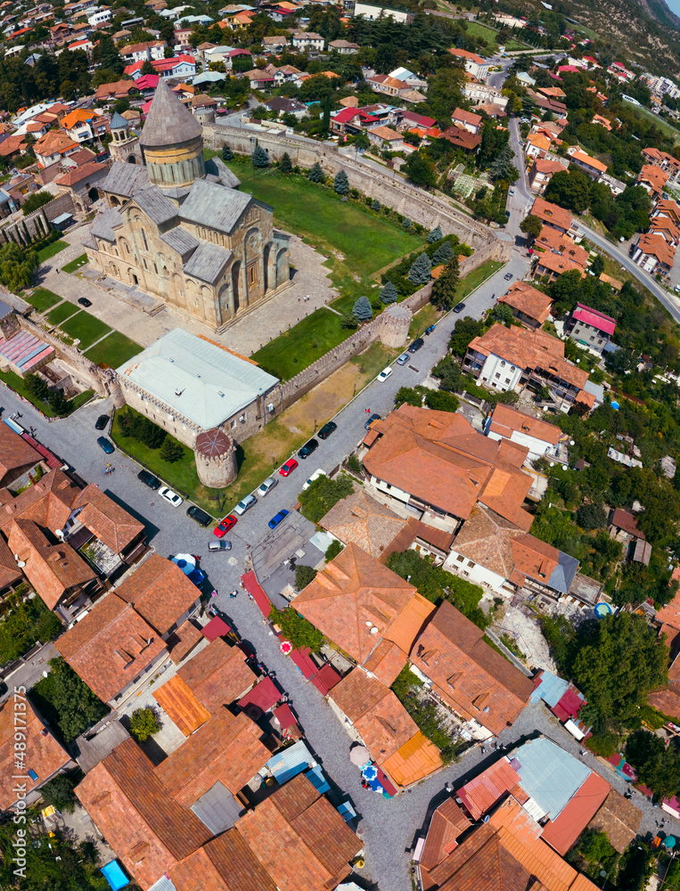 Beautiful aerial view of streets of Mtskheta village in Georgia. Mtkvari river. Summer sunny day. Travel and vacation. Svetitskhoveli Cathedral fortress. Vertical photo