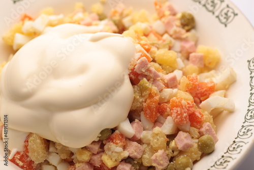 Russian salad Olivier with mayonnaise on plate. Light background. Top view, flat lay.