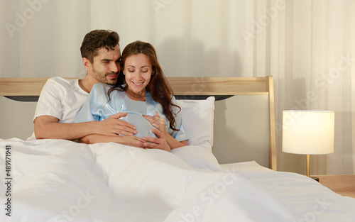 Obraz na plátně Cheerful husband enjoy embracing pregnant wife and happy to tenderly fondle belo