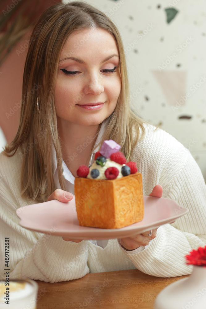 blond girl cube formed dessert with cream, raspberry, blueberry and marshmallow topping closeup photo blond girl cube formed dessert with cream, raspberry, blueberry and marshmallow topping closeup photo