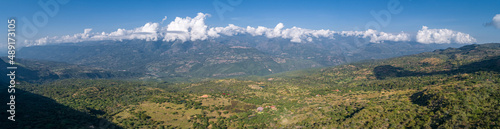 Panoramic aerial view from the plateau to the valley and adjacent mountains covered with white clouds, blue Sky, Barichara, Colombia