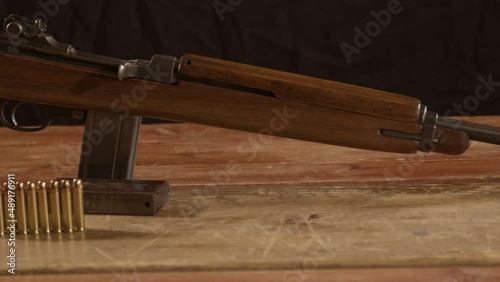 Wide Dolly of classic 30m1 carbine rifle with ammunition on the foreground standing on a wooden surface photo