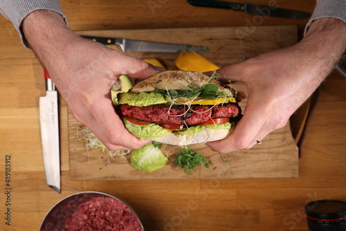 Vegetarian beetroot mango burger holding by a chef photo