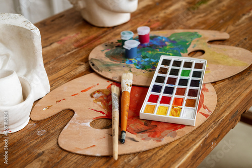 Painter artist wooden workplace with warecolor aquarelle palette, paintbrushes and paints