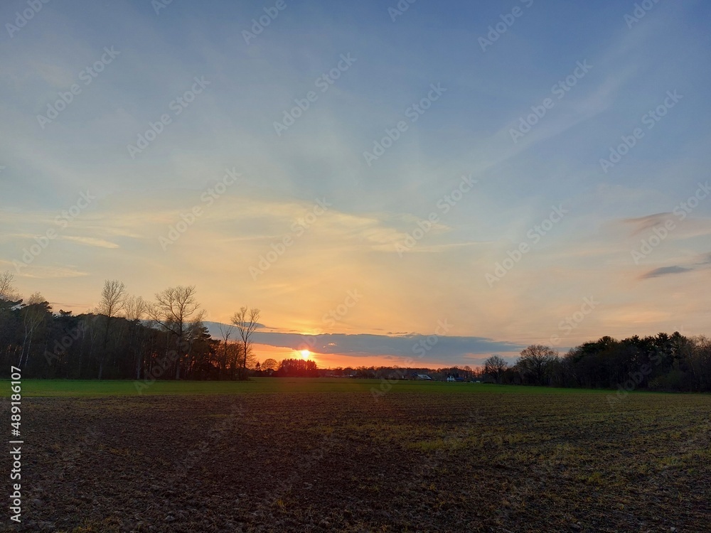 Dämmerung auf einer Agrarlandschaft. Der Himmel wird dunkel. Die Sonnenuntergänge im Westen mit Rötung. Der Mond erscheint am Himmel über der Wiese. Der Wald verwandelt sich in Silhouetten. Abend. Dämmerung auf einer Agrarlandschaft. Der Himmel wird dunkel. Die Sonnenuntergänge im Westen mit Rötung. Der Mond erscheint am Himmel über der Wiese. Der Wald verwandelt sich in Silhouetten. Abend.
