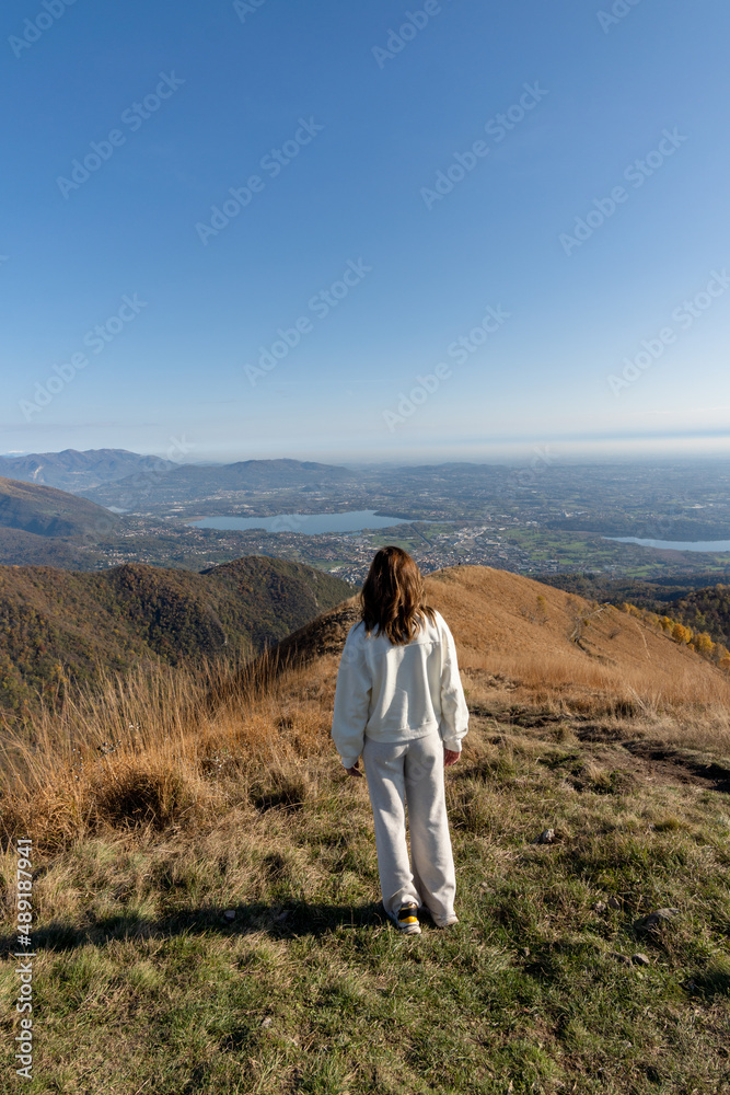 Traveler woman dressed in white on top of mountain admiring landscape of lago di como italy