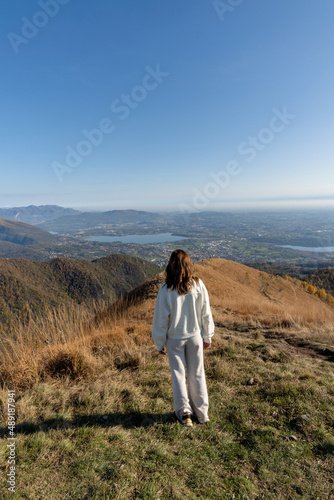 Traveler woman dressed in white on top of mountain admiring landscape of lago di como italy