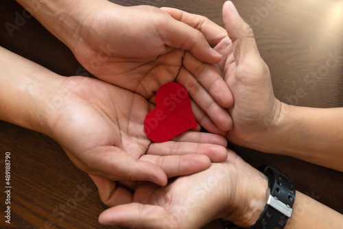 Fototapeta Naklejka Na Ścianę i Meble -  Hands of Couple holding Red Heart Symbol